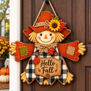 May include: A decorative scarecrow door hanger featuring a hessian hat with a sunflower, a black and white buffalo check shirt, and a tan sign with the text Hello Fall. The scarecrow has straw-like accents, patches, and a jute rope hanger.