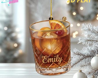Può includere: Un ornamento piatto 2D a forma di bicchiere da cocktail, con una bevanda con ghiaccio, una fetta d'arancia e una ciliegia. Il bicchiere ha un bordo dorato e il nome "Emily" è inciso sul davanti. L'ornamento è sospeso da un filo d'oro.