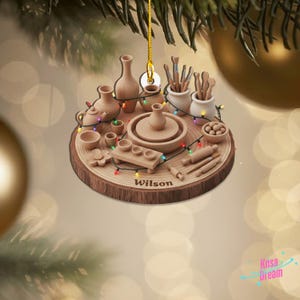 May include: A wooden Christmas ornament featuring a pottery theme. The ornament includes miniature pottery tools, a pottery wheel, and various pottery pieces. The name "Wilson" is inscribed on the ornament, which is decorated with colorful lights.