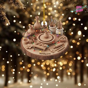 May include: Wooden ornament featuring pottery tools and miniature pottery items, including a pottery wheel, vases, and brushes. The ornament is shaped like a wood slice and includes the name "Wilson". Decorative lights are strung around the pottery items.