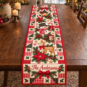 May include: A rectangular quilted table runner featuring a festive Christmas theme with a snowman, a deer, a lantern, candy canes, poinsettias, and pine branches. The text The Andersons is printed in red script at the bottom of the runner.