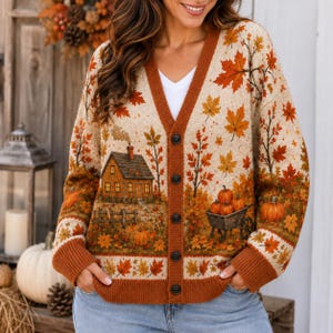 Peut inclure: Un gilet beige à col en V avec une fermeture boutonnée et des bordures orange foncé. Le tricot présente une scène automnale avec une petite maison, une clôture en bois, une brouette remplie de citrouilles et des feuilles d'érable orange.