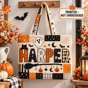 May include: A quilted tote bag featuring a Halloween theme with the name HARPER printed in large letters. The design includes ghosts, black cats, pumpkins, bats, stars, moons, and spiderwebs in orange, black, and cream colours. Text reads PRINTED - NOT EMBROIDERED.