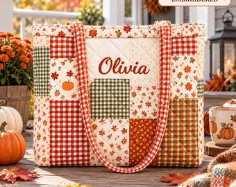 Può includere: Una borsa tote trapuntata con un design patchwork a tema autunnale che include zucche, motivi a quadretti rossi e verdi e foglie autunnali. Il nome Olivia è stampato in rosso sul davanti. Un'etichetta riporta PRINTED - NOT EMBROIDERED.
