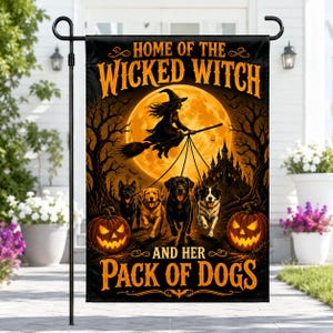 Puede incluir: Una bandera de jardín rectangular con la silueta negra de una bruja en una escoba frente a una gran luna llena naranja. Debajo, cuatro perros corren hacia adelante, flanqueados por dos calabazas brillantes. Texto: HOME OF THE WICKED WITCH AND HER PACK OF DOGS.