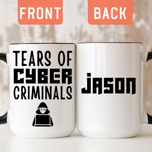 May include: A white ceramic mug with a black handle and rim. The front features the black text "TEARS OF CYBER CRIMINALS" above a graphic of a hooded figure at a computer. The back displays the name "JASON" in a bold, black, block-style font.