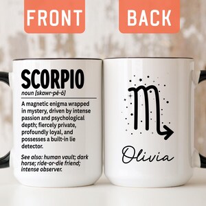 May include: A white ceramic mug with a black handle and interior. The front features the text SCORPIO, a definition, and related terms. The back displays a black Scorpio zodiac symbol, small stars, and the name Olivia in a script font.