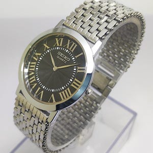 Vintage Seiko Quartz Slim Herrarmbandsur med romerska siffror, svart texturerad urtavla, renoverat japanskt armbandsur