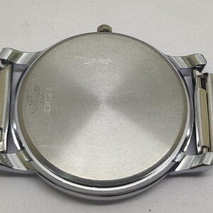 Puede incluir: Un reloj de pulsera plateado con una correa de malla. La caja del reloj es redonda con una parte trasera plateada y un bisel plateado. La correa de malla es de color plata clara y est&aacute; unida a la caja del reloj con conectores plateados y dorados.