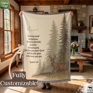 May include: A beige throw blanket with a forest scene featuring deer and pine trees. The blanket has a fringed edge and text that reads "Be strong and courageous..." and "Fully Customizable!"
