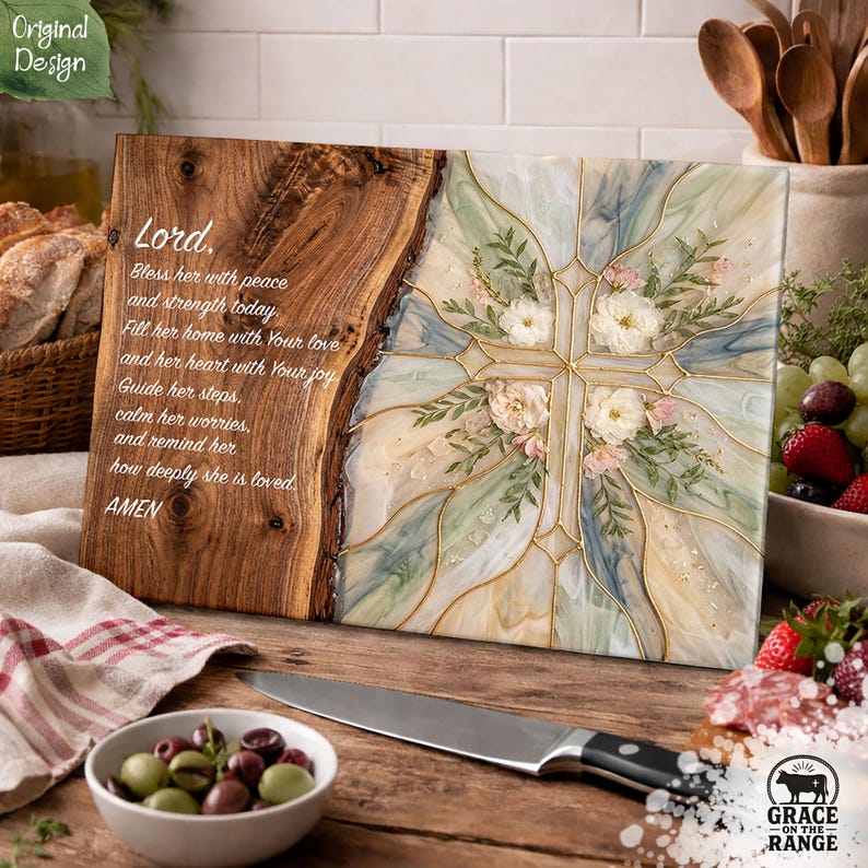 May include: A rectangular wooden serving board featuring a natural live edge on the left side with engraved text starting with Lord, Bless her with peace and strength today. The right side has a resin inlay with a floral cross design.