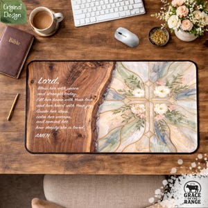 May include: A rectangular mousepad with a wooden grain design on the left and a floral cross design on the right. The mousepad has the text "Lord" and a prayer. The mousepad is on a wooden desk with a Bible, coffee, and a keyboard.