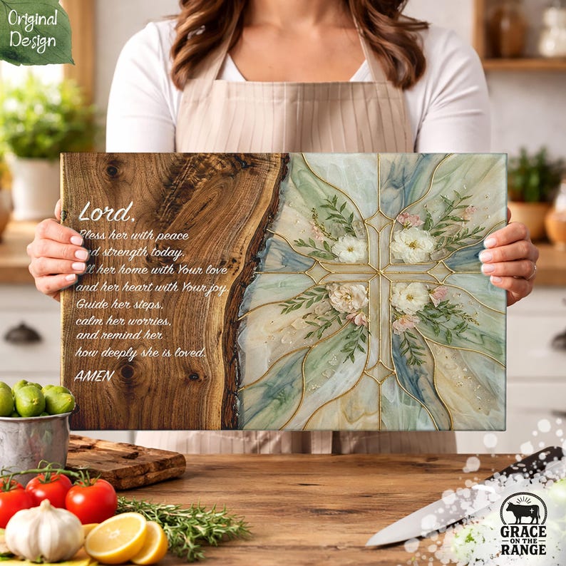 May include: A rectangular wooden wall plaque featuring a natural live edge on the left side and a resin-filled right side with a cross design. The wood displays the text: Lord, Bless her with peace and strength today, fill her home with Your love and her heart with Your joy. Guide her steps, calm her worries, and remind her how deeply she is loved. AMEN. The resin section contains pressed white flowers and green foliage encased in swirling blue, green, and white patterns.