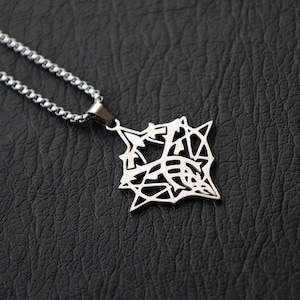 May include: A silver-colored pendant necklace with a geometric design. The pendant is a square shape with an intricate, openwork pattern. The chain is a classic curb style, and the background is a textured black surface.