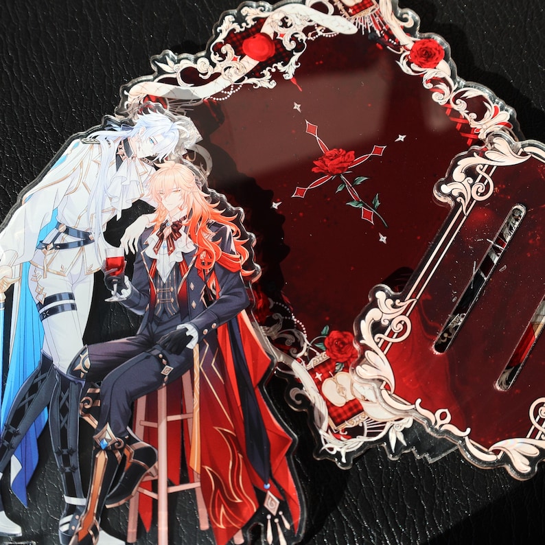May include: Acrylic charms featuring anime-style illustrations. One charm depicts two figures, one in white and blue, the other in a black suit with red accents. The other charm is a dark red design with roses and decorative elements.