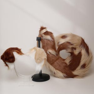 以下が含まれることがあります： 茶色、白、タン色のフェイクファーの尻尾と、耳付きのお揃いのヘッドバンド。 尻尾はカールしており、黒いスタンドで支えられています。 ヘッドバンドは、茶色とタン色のアクセントが付いた白い毛皮が特徴です。