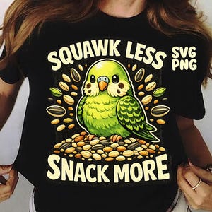 May include: Black t-shirt featuring a green parrot illustration surrounded by seeds. The text "SQUAWK LESS SNACK MORE" is displayed above and below the parrot. The words "SVG PNG" are in the upper right corner.