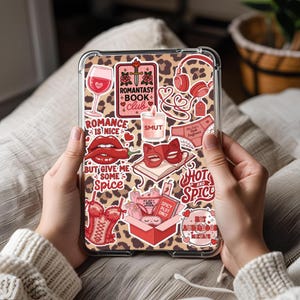 May include: A clear tablet case with a leopard print design, covered in stickers with a romance theme. Stickers include a wine glass, lips, a corset, and text that reads "Romantasy Book Club", "Smut", and "Hot and Spicy".