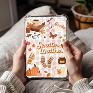 May include: A clear tablet case featuring a pink and white gingham pattern, decorated with autumn-themed stickers. Stickers include pumpkins, coffee, books, socks, and the words "Sweater Weather."