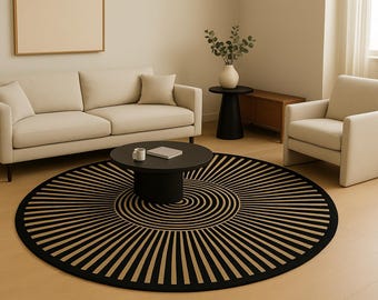 May include: A modern living room setup featuring a beige sofa, armchair, and a round black coffee table. A black and beige patterned rug is centered on the floor. A vase with greenery sits on a side table.