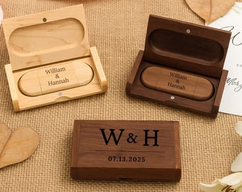Op de afbeelding: Twee houten USB-sticks in bijpassende rechthoekige houten doosjes. Eén doosje is van licht esdoornhout, de andere van donker walnoothout. Beide sticks zijn gegraveerd met "William & Hannah". Een gesloten walnoothouten doosje toont "W & H" en "07.13.2025".