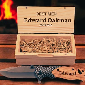May include: A wooden box with the text "BEST MEN" and the name "Edward Oakman" and the date "03.19.2025" engraved on the lid. Inside the box is shredded paper. A folding knife with a gray blade and wooden handle is in front of the box.