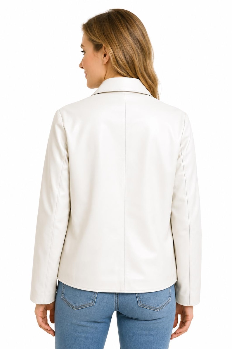 May include: A cream-coloured blazer with long sleeves and a collared neckline. The jacket is paired with blue jeans. The back view of the jacket shows a tailored fit. The blazer is made of a smooth, possibly leather-like material.