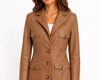 May include: A tan leather blazer with a classic design. The jacket features a notched collar, four front pockets, and decorative buttons. The blazer has a tailored fit and is suitable for various occasions.