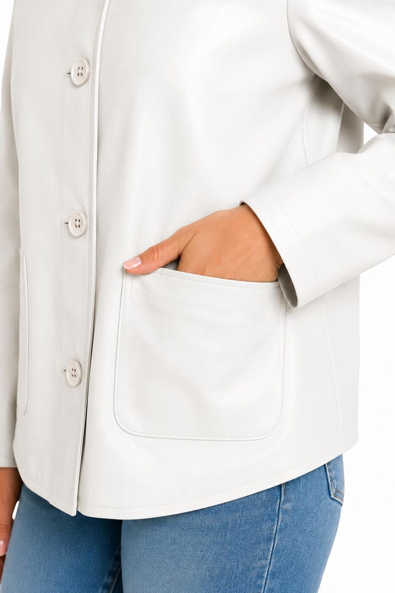 May include: A cream-coloured jacket with a classic design. The jacket has a button-up front, two front pockets, and a tailored fit. The jacket is made of a smooth material. The model is wearing blue jeans.