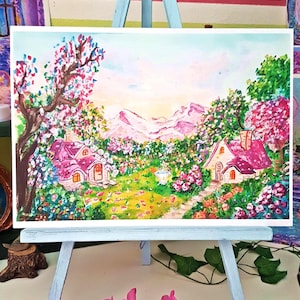 Può includere: Un dipinto paesaggistico su un cavalletto azzurro raffigurante due piccoli cottage con tetti rosa brillante immersi in un giardino rigoglioso. La scena include alberi in fiore, fiori vivaci, un sentiero in pietra e montagne in lontananza.