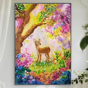 May include: A framed painting depicts a deer standing in a colorful garden under a tree. The artwork features a brown deer, a brown tree trunk, and vibrant flowers in shades of pink, purple, yellow, and blue. The painting is set against a light background.