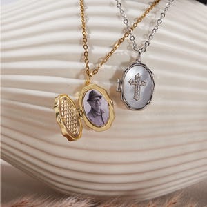 Puede incluir: Dos collares con colgantes ovalados. Uno es dorado y se abre para revelar una pequeña foto. El otro es plateado con un diseño de cruz. Ambos colgantes cuelgan de delicadas cadenas.