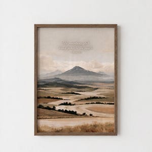 以下が含まれることがあります： 曇り空の下に広がる丘陵と遠くの山を描いた風景画の額入りアートプリント。画像の中央には「The mountains shall bring peace to the people」というテキストが白い筆記体で印刷されています。