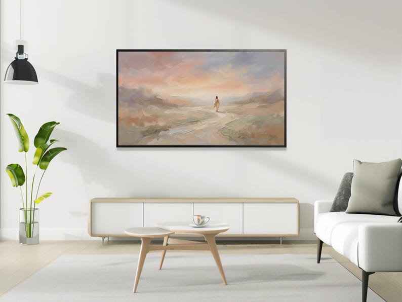 K&ouml;nnte beinhalten: Abstrakte Landschaftsmalerei in einem schwarzen Rahmen. Das Kunstwerk zeigt eine Figur, die auf einem Pfad geht, mit einer sanften Farbpalette aus Pfirsich, Blau und Beige. Das Gem&auml;lde h&auml;ngt &uuml;ber einem wei&szlig;en Schrank und einem hellfarbigen Teppich.
