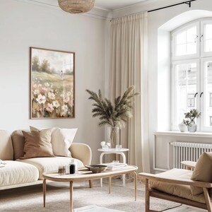 May include: A living room scene with a beige sofa, wooden coffee table, and a framed floral painting. The room features a large window with cream-colored curtains, a woven light fixture, and decorative plants in vases, creating a warm and inviting atmosphere.