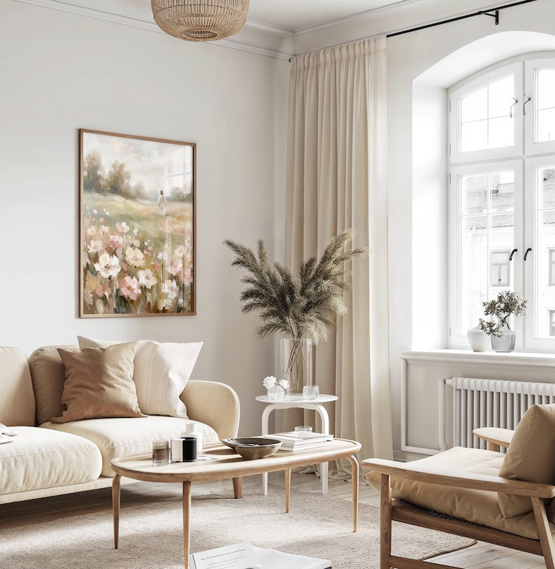 May include: A living room scene with a beige sofa, wooden coffee table, and a framed floral painting. The room features a large window with cream-colored curtains, a woven light fixture, and decorative plants in vases, creating a warm and inviting atmosphere.