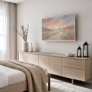 K&ouml;nnte beinhalten: Schlafzimmer-Szene mit einer hellen Holzkommode und einem gerahmten Gem&auml;lde dar&uuml;ber. Das Gem&auml;lde zeigt eine Figur auf einem Weg unter einem farbenfrohen Himmel. Dekorative Vasen, eine Schale und schwarze Laternen stehen auf der Kommode.