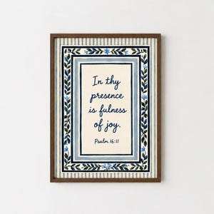 Könnte beinhalten: Ein gerahmter Kunstdruck mit cremefarbenem Zentrum und dem dunkelblauen Text In thy presence is fulness of joy. Psalm 16:11. Das Design ist von einer dekorativen Bordüre aus blauen Blättern und Blumen auf hellblau gestreiftem Hintergrund umgeben.