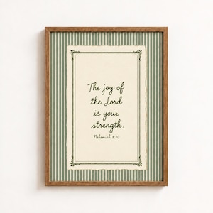 Peut inclure: Une affiche murale encadrée présentant un insert en papier crème avec le texte "The joy of the Lord is your strength. Nehemiah 8:10" en écriture cursive vert foncé. L'impression est placée sur un fond à rayures verticales vert sauge et blanc.
