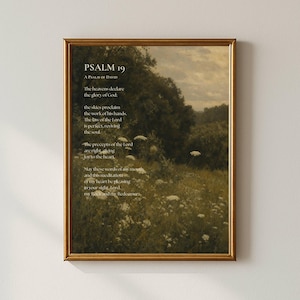 Peut inclure: Une impression d'art encadrée représentant un paysage de prairie avec des fleurs sauvages blanches et des arbres sous un ciel nuageux. Le texte Psaume 19, Psaume de David, et des versets bibliques sont imprimés en blanc sur le paysage vert et brun.