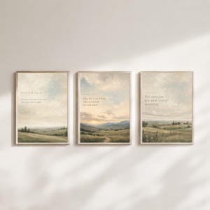 May include: Three framed prints displaying landscape scenes with uplifting quotes. The prints feature countryside vistas with text from Isaiah and Romans. The frames are a light wood colour, and the overall aesthetic is calming and neutral.