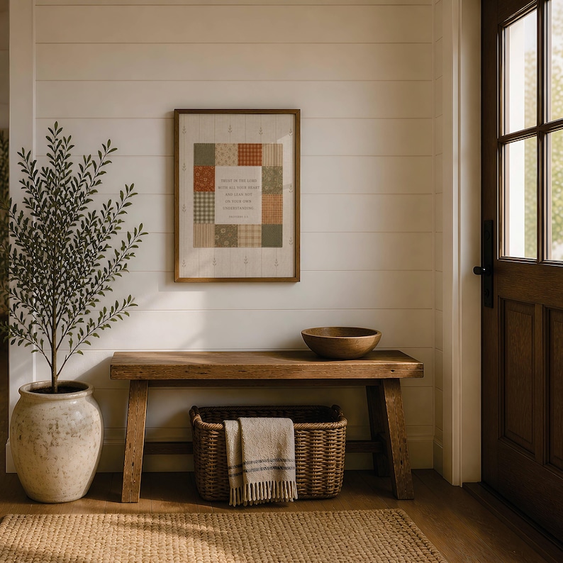 May include: A framed wall art print featuring a patchwork grid of muted orange, green, and cream patterns surrounding the text Trust in the Lord with all your heart and lean not on your own understanding, displayed in a wooden frame on a white wall.