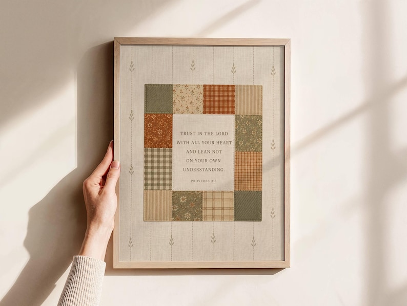 May include: A framed wall art print featuring a central square block of patchwork fabric patterns in shades of olive green, rust orange, and cream. The center contains the text: Trust in the Lord with all your heart and lean not on your own understanding. Proverbs 3:5.