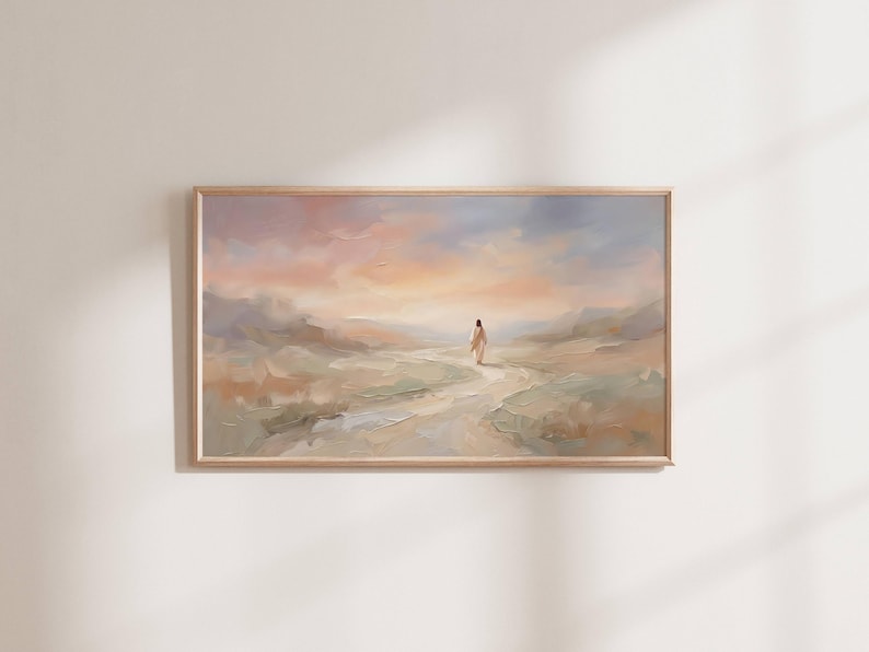 K&ouml;nnte beinhalten: Ein &Ouml;lgem&auml;lde in einem hellen Holzrahmen zeigt eine Figur, die auf einem Pfad durch eine Landschaft geht. Der Himmel geht von Pfirsich zu Blau &uuml;ber. Das Kunstwerk weckt ein Gef&uuml;hl von Frieden und Gelassenheit.