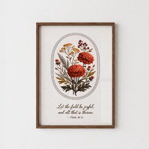 Peut inclure: Une impression d'art encadrée présentant une illustration ovale centrale de fleurs orange et jaunes avec un feuillage vert. Sous la composition florale, le texte indique : Let the field be joyful, and all that is therein. — Psalm 96:12.