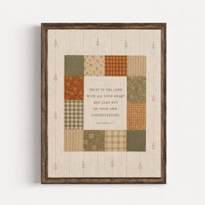 May include: A framed wall art piece featuring a central cream-colored panel with the text "TRUST IN THE LORD WITH ALL YOUR HEART AND LEAN NOT ON YOUR OWN UNDERSTANDING. PROVERBS 3:5" surrounded by a border of assorted fabric squares in earth tones.