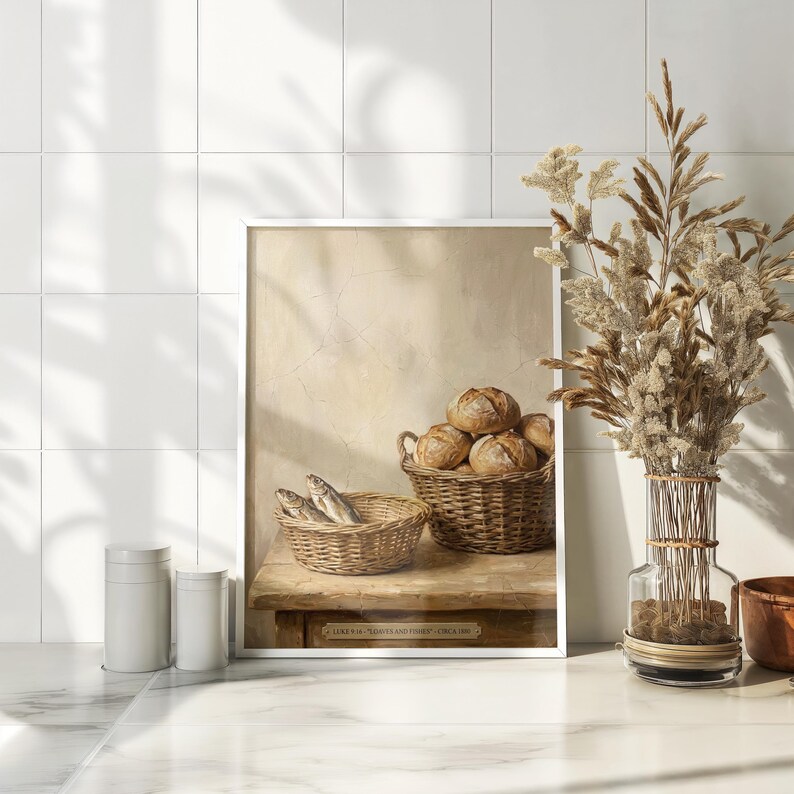 May include: A framed print depicting a still life with two wicker baskets. One basket holds several round loaves of bread, and the other contains fish. The print is set on a wooden table against a neutral background. The text on the print reads "Luke 9:16 'Loaves and Fishes' Circa 1880."