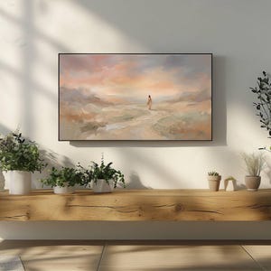 K&ouml;nnte beinhalten: Abstrakte Landschaftsmalerei in einem schwarzen Rahmen. Das Kunstwerk zeigt eine Figur, die auf einem Pfad auf einen Sonnenuntergang mit sanften Pastellfarben zugeht. Das Gem&auml;lde ist &uuml;ber einem Holzregal mit verschiedenen Pflanzen angebracht.