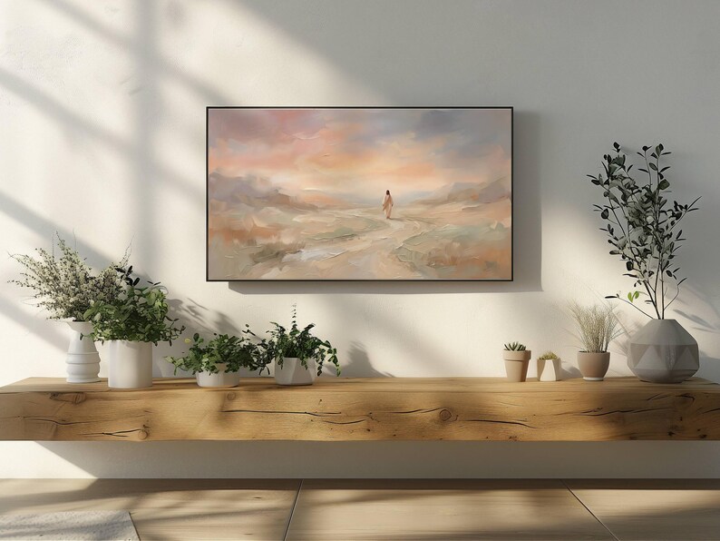 K&ouml;nnte beinhalten: Abstrakte Landschaftsmalerei in einem schwarzen Rahmen. Das Kunstwerk zeigt eine Figur, die auf einem Pfad auf einen Sonnenuntergang mit sanften Pastellfarben zugeht. Das Gem&auml;lde ist &uuml;ber einem Holzregal mit verschiedenen Pflanzen angebracht.