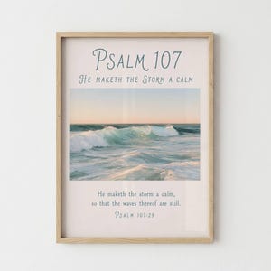 Può includere: Una stampa artistica incorniciata con una fotografia di onde oceaniche al tramonto. Il testo recita: Psalm 107, He maketh the storm a calm, e He maketh the storm a calm, so that the waves thereof are still, Psalm 107:29. La cornice è in legno chiaro.